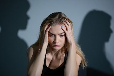 Женщина держится за голову на заднем фоне тени